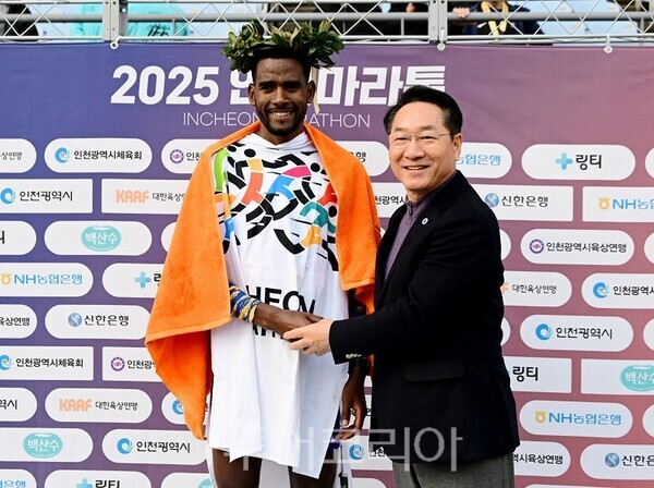 유정복 인천광역시장이 23일 문학경기장에서 열린 '2025 인천마라톤'에서 우승 선수에게 월계관을 씌워주고 있다.